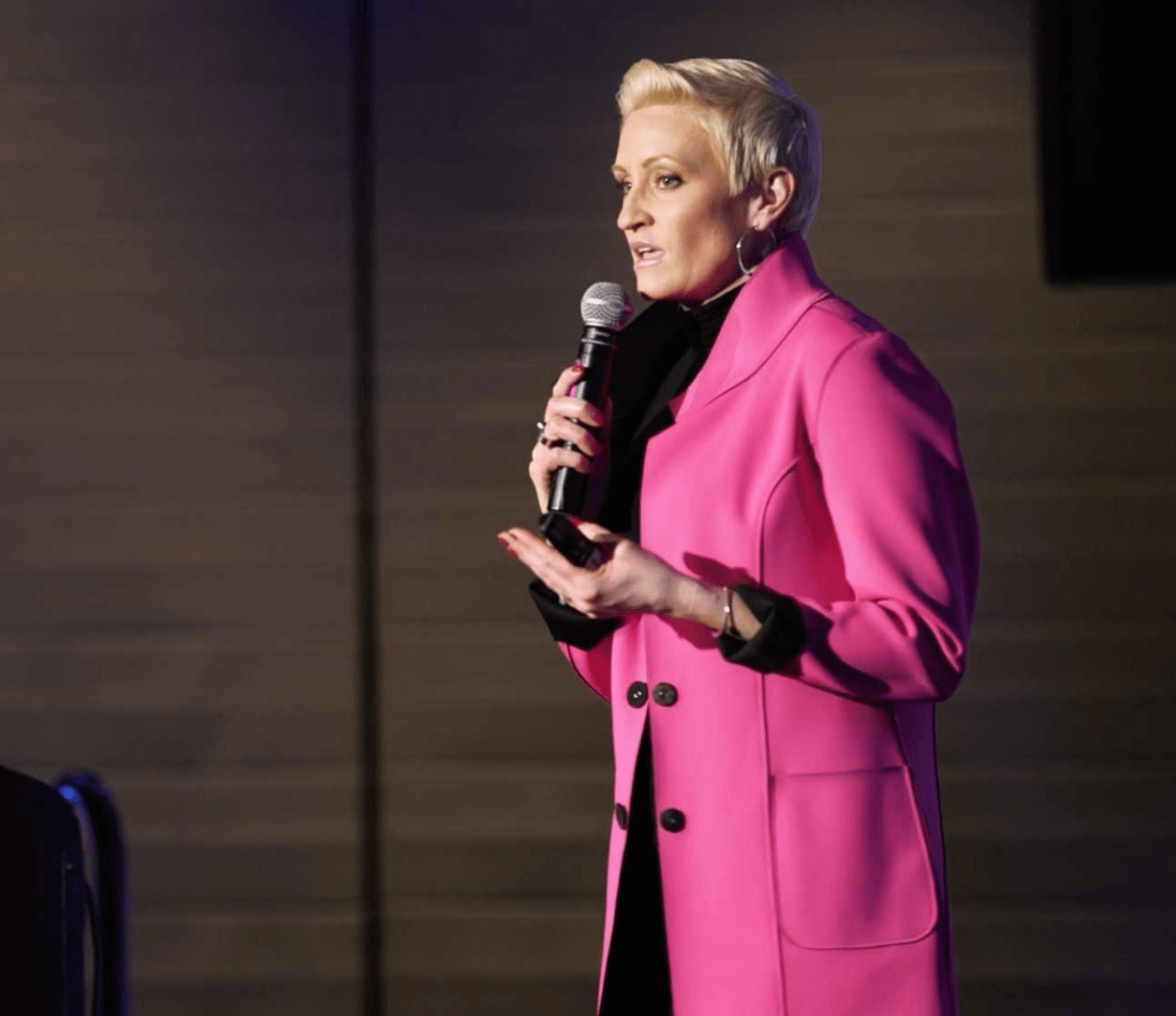 keynote speaker holding microphone wearing bright pink jacket